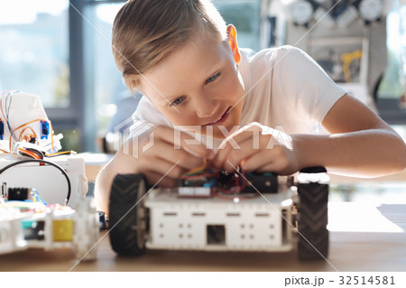 Adorable kid fixing wires in robotic vehicle 32514581