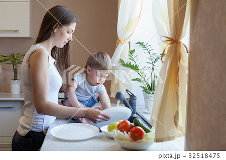 the little boy is helping mom in the kitchen 32518475