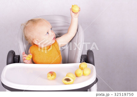 Cute toddler eating an apricot in baby chair 32519750