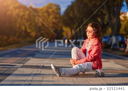 girl wearing helmet sitting on a skateboard in 32521441