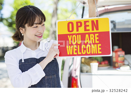 キッチンカー オープン 看板を持つ女性の写真素材