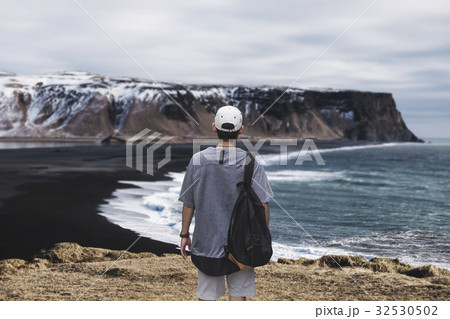 Young man with backpack standing on cliff Young man with backpack standing on cliff 32530502