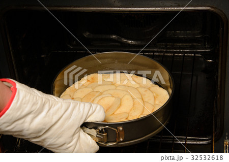 Close up of woman putting apple pie inside oven with gloves in her hand Close up of woman putting apple pie inside oven with gloves in her hand 32532618