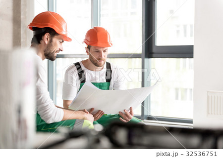 Cheerful builder with orderly colleague watching 32536751