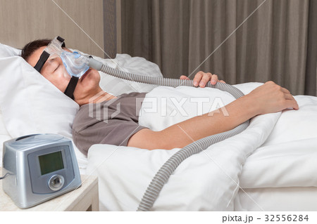 middle age asian man sleeping in bed wearing CPAP 32556284