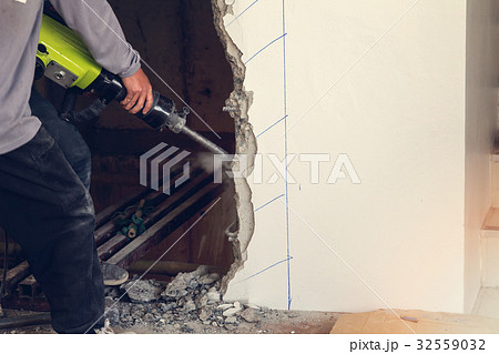 Worker using a jackhammer to drill into wall. Worker using a jackhammer to drill into wall. 32559032