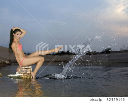 Young woman sitting on the stone splashing water 32559146