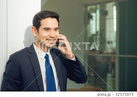 Handsome businessman in suit speaking on phone Handsome businessman in suit speaking on phone 32573075