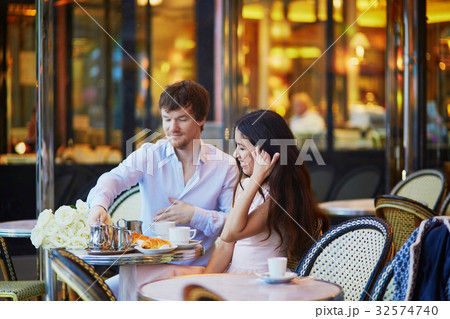 Couple drinking coffee and eating croissants in Parisian cafe 32574740