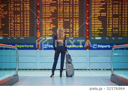 Woman with hand luggage in international airport terminal, looking at information board Woman with hand luggage in international airport terminal, looking at information board 32576864