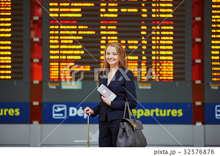 Woman with hand luggage in international airport terminal, looking at information board Woman with hand luggage in international airport terminal, looking at information board 32576876
