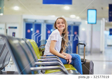 Tourist girl with backpack and carry on luggage in international airport, waiting for flight Tourist girl with backpack and carry on luggage in international airport, waiting for flight 32577019