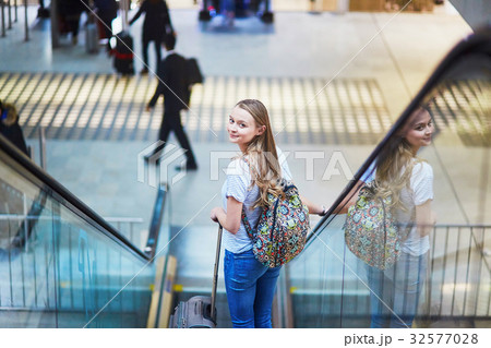 Tourist girl with backpack and carry on luggage in international airport, on escalator Tourist girl with backpack and carry on luggage in international airport, on escalator 32577028