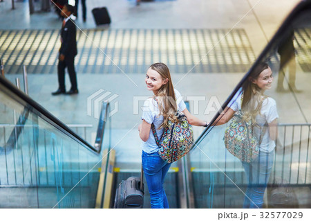 Tourist girl with backpack and carry on luggage in international airport, on escalator Tourist girl with backpack and carry on luggage in international airport, on escalator 32577029