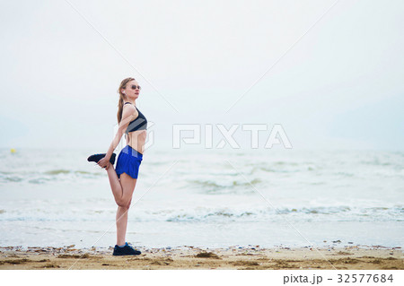 Woman on beach doing stretching exercise after a workout Woman on beach doing stretching exercise after a workout 32577684