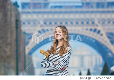 Girl with traditional French baguette near the Eiffel tower Girl with traditional French baguette near the Eiffel tower 32577782