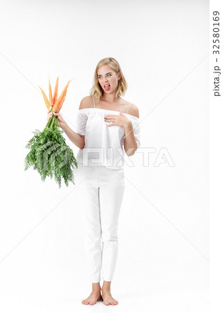 blond woman holding carrot with green leaves on 32580169