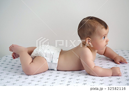 naked baby in diapers lying on her belly 32582116