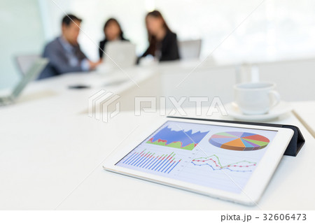 Digital tablet showing graph with business partners discussing in meeting room 32606473