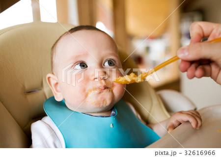 Unrecognizable mother at home feeding her baby son 32616966