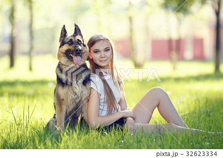 Teenage girl with her dog sitting in park Teenage girl with her dog sitting in park 32623334