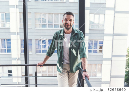 Cheerful stylish guy is standing on staircase Cheerful stylish guy is standing on staircase 32628640