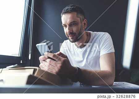 Pleasant guy is typing message on smartphone Pleasant guy is typing message on smartphone 32628876
