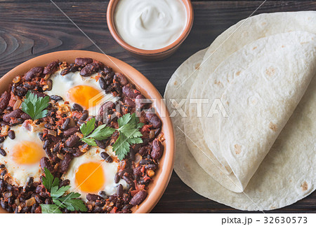 Bowl of chipotle bean chili with baked eggs 32630573