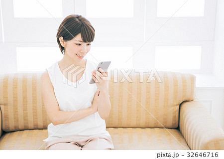 部屋でスマホを使う女性（※婚活、結婚相談所等のサイトやアプリなどでのご利用はお控えください） 32646716