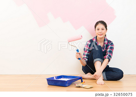 woman with roller applying pink paint 32650075