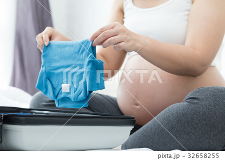 Pregnant woman is packing baby clothes 32658255