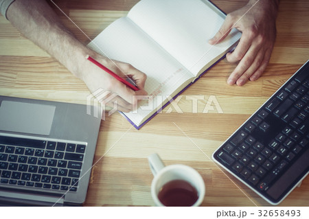 Top view of freelancer man writing in notebook at Top view of freelancer man writing in notebook at 32658493