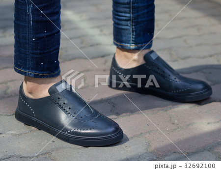 Blue leather sneakers dressed on a man in jeans Blue leather sneakers dressed on a man in jeans 32692100