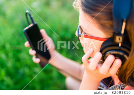 Teen girl listening to music with her headphones outdoor Teen girl listening to music with her headphones outdoor 32693810