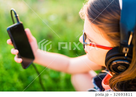 Teen girl listening to music with her headphones outdoor Teen girl listening to music with her headphones outdoor 32693811