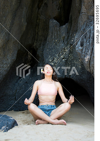 Girl practicing yoga in the shade of a beach cave Girl practicing yoga in the shade of a beach cave 32695695