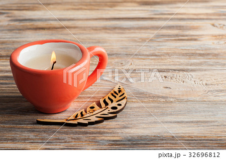 Candle in coral cup over shabby wooden background Candle in coral cup over shabby wooden background 32696812