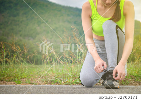 Young woman tying her sports shoes on exercising Young woman tying her sports shoes on exercising 32700171