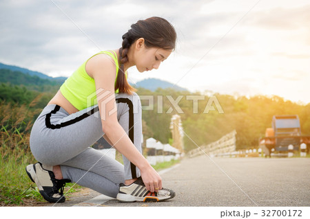 Young woman tying her sports shoes on exercising Young woman tying her sports shoes on exercising 32700172