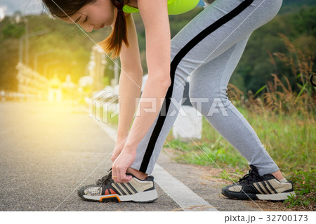 Young woman tying her sports shoes on exercising  32700173