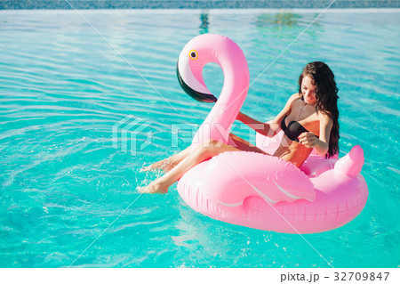 girl sits on inflatable mattress flamingos in pool 32709847