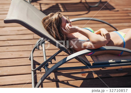 young woman swimsuit laying chaise-longue poolside young woman swimsuit laying chaise-longue poolside 32710857