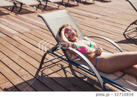 young woman swimsuit laying chaise-longue poolside young woman swimsuit laying chaise-longue poolside 32710858
