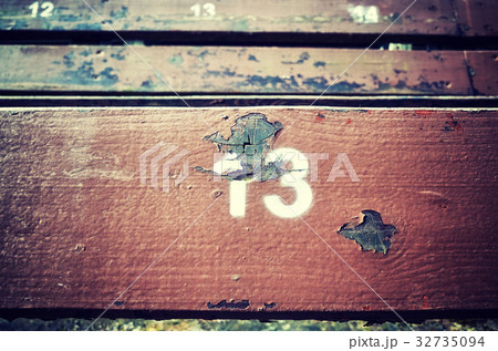 Number thirteen painted on an old wooden seat. 32735094