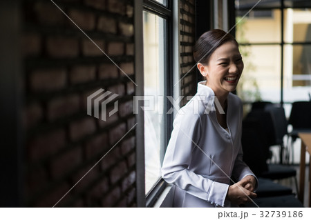 A smiling woman is standing near the window 32739186