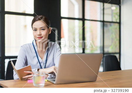 The business woman is holding the notebook and looking at something. The business woman is holding the notebook and looking at something. 32739190