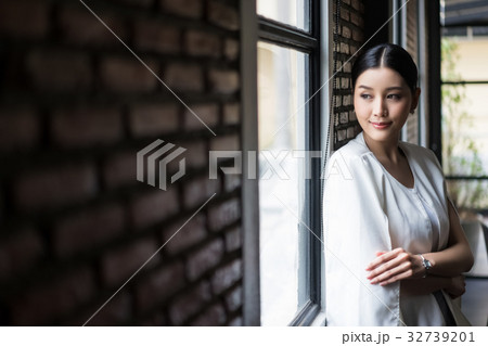 A picture of a woman standing alone at the window. 32739201