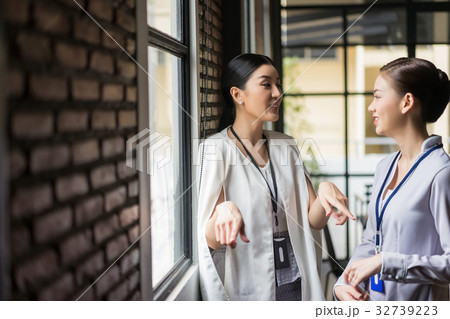 a business woman is talking to her colleague near by window a business woman is talking to her colleague near by window 32739223