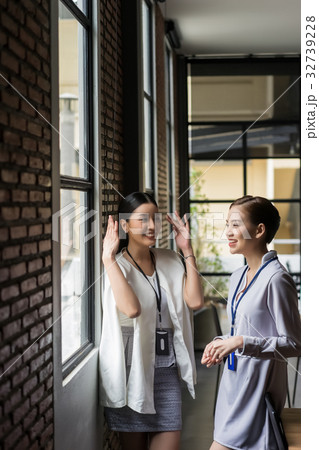 a couple of girls is standing and chatting near the window a couple of girls is standing and chatting near the window 32739228
