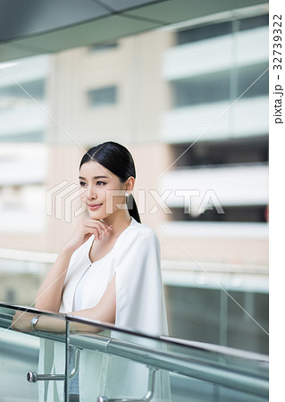 a young woman is leaning on a balcony and looking at something a young woman is leaning on a balcony and looking at something 32739322
